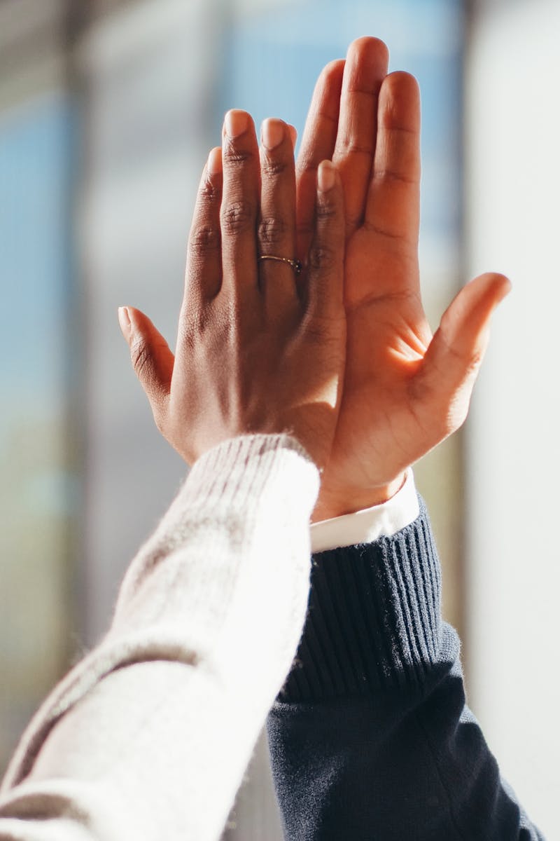 Close-up of two diverse people's hands high-fiving in a gesture of success and teamwork.
